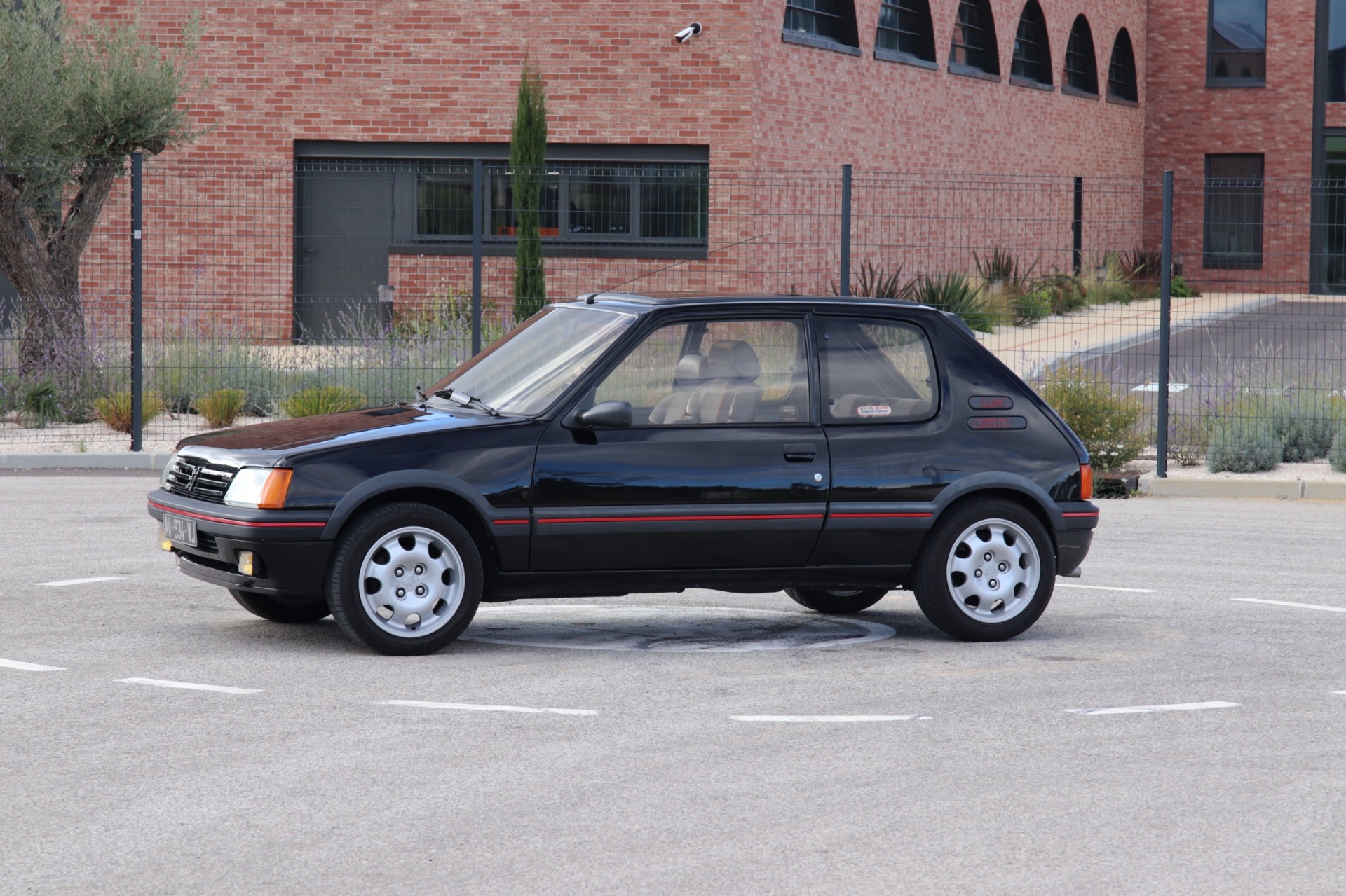Peugeot 205 GTI 1.9 noire de profil gauche sur parking