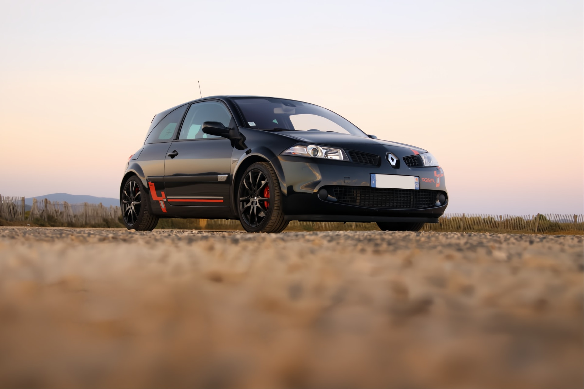 Mégane R26.R noire photographiée de trois quarts avant sur route