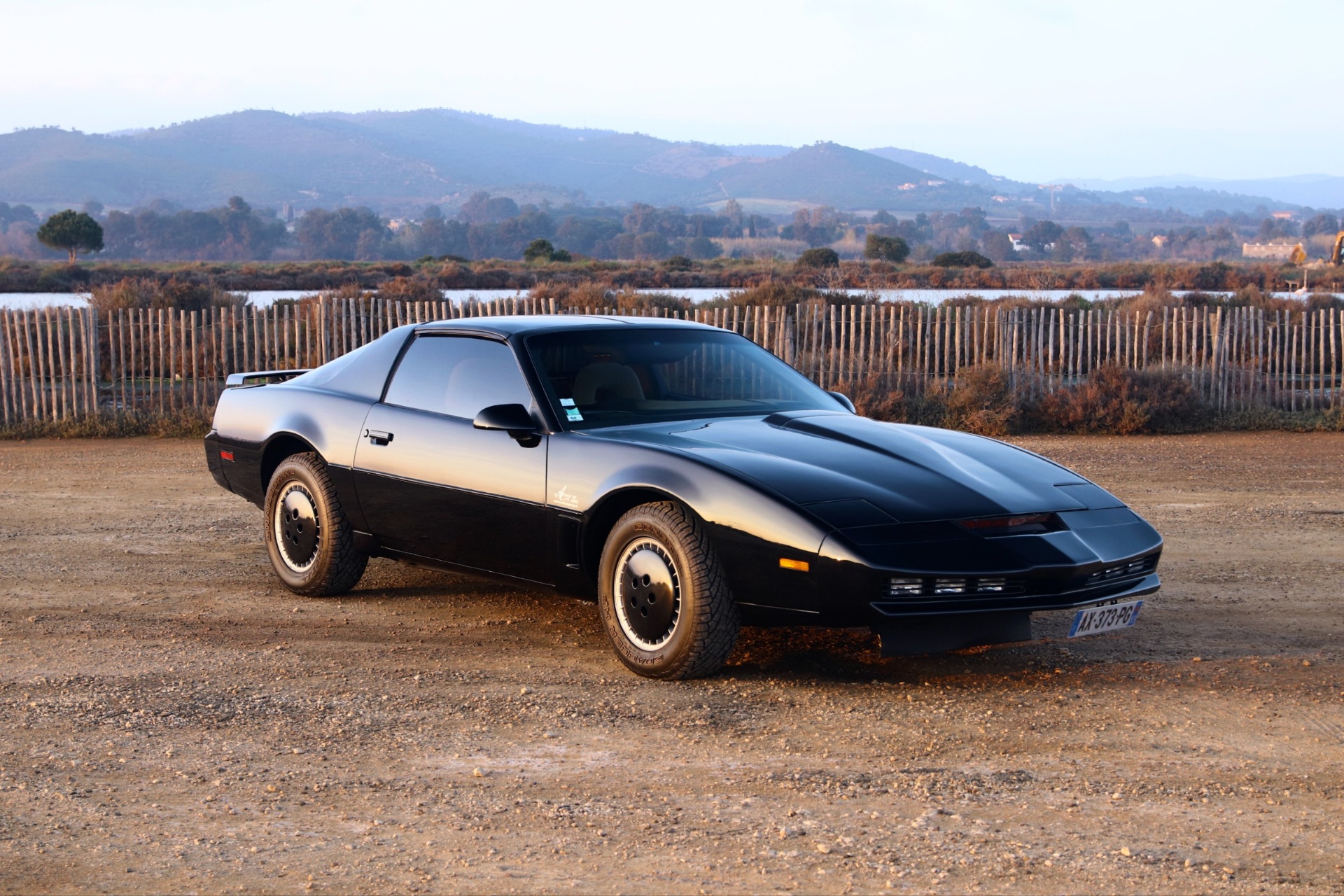 KITT K2000 réplique Pontiac Firebird Trans Am noire de trois-quarts avant au coucher du soleil
