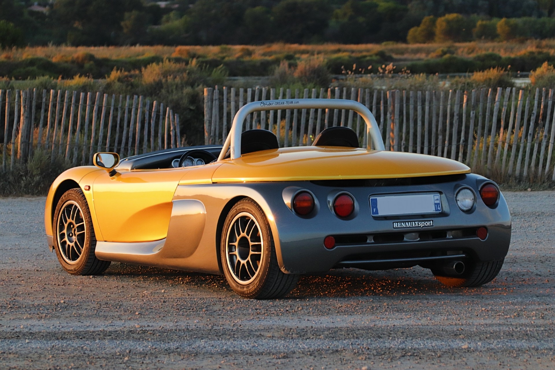 Renault Sport Spider jaune et gris de trois quarts arrière au coucher du soleil