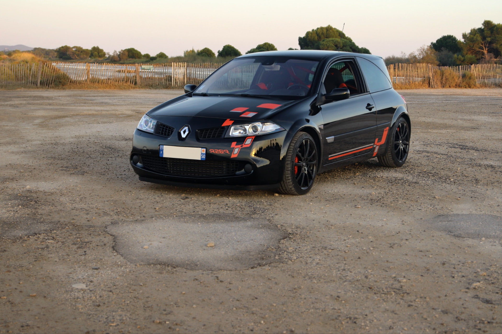 Mégane R26.R noire vue de trois quarts avant, jantes noires et marquages rouges