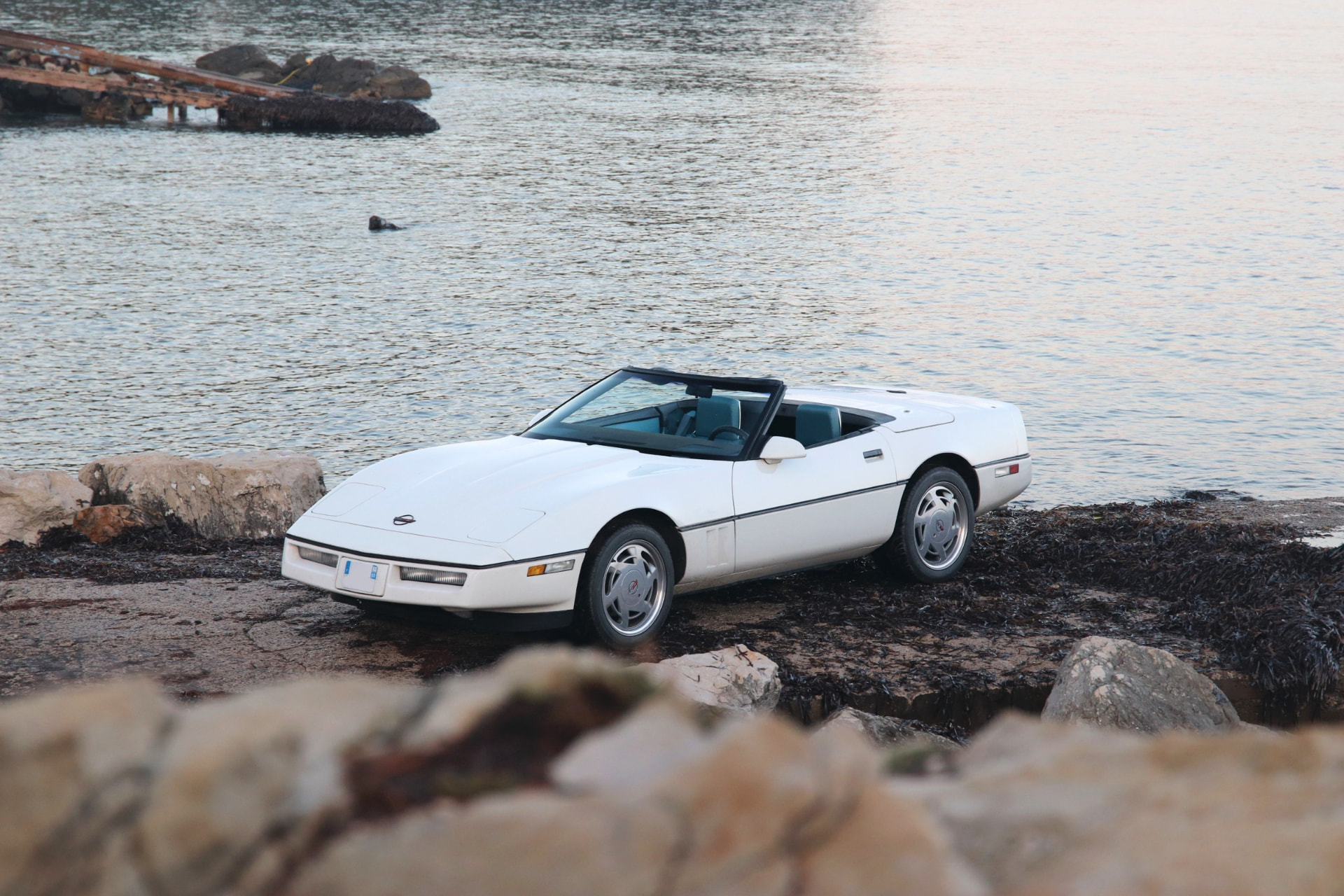 Corvette C4 cabriolet blanc capote ouverte au bord de l'eau