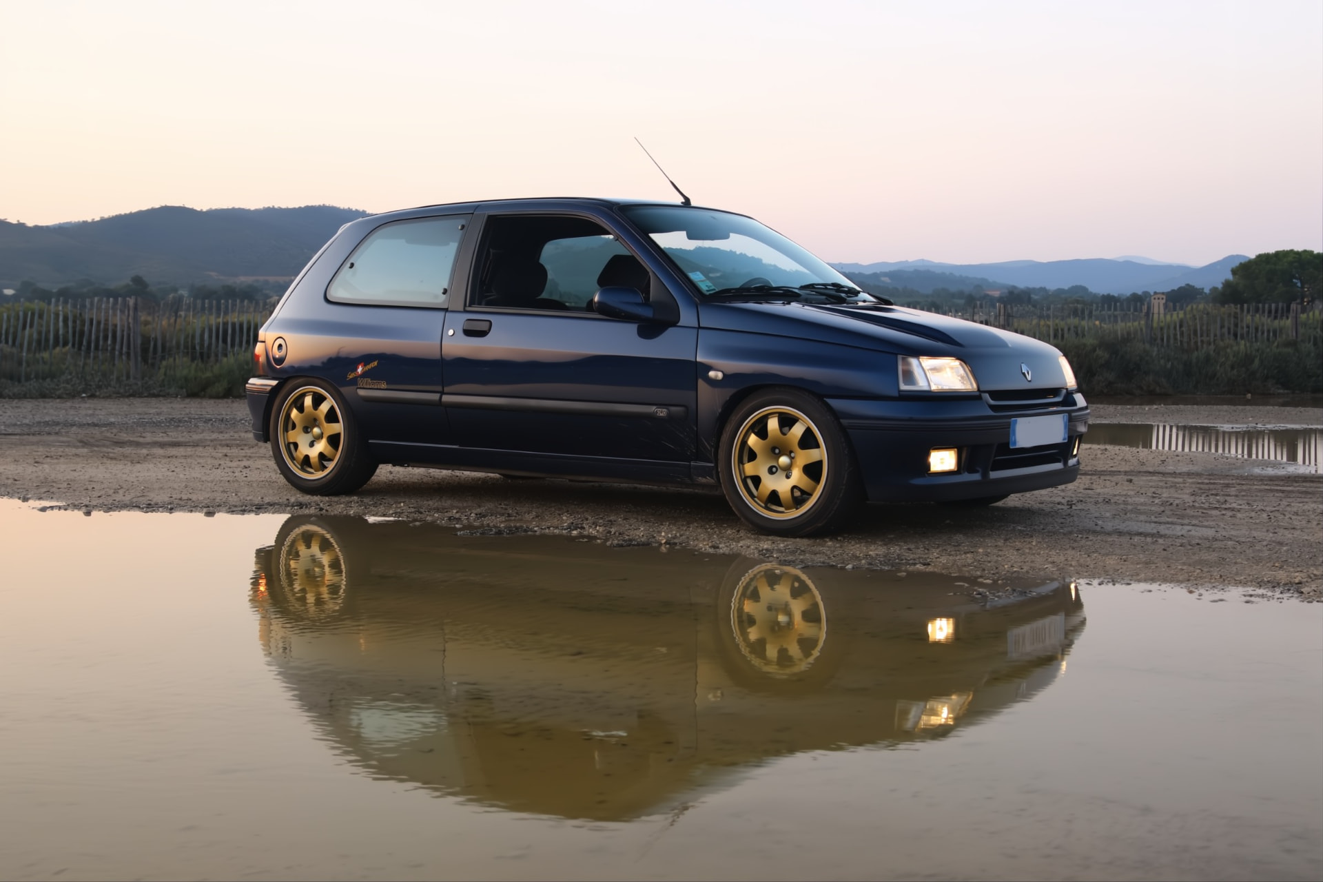 Renault Clio Williams bleue et ses jantes dorées au crépuscule
