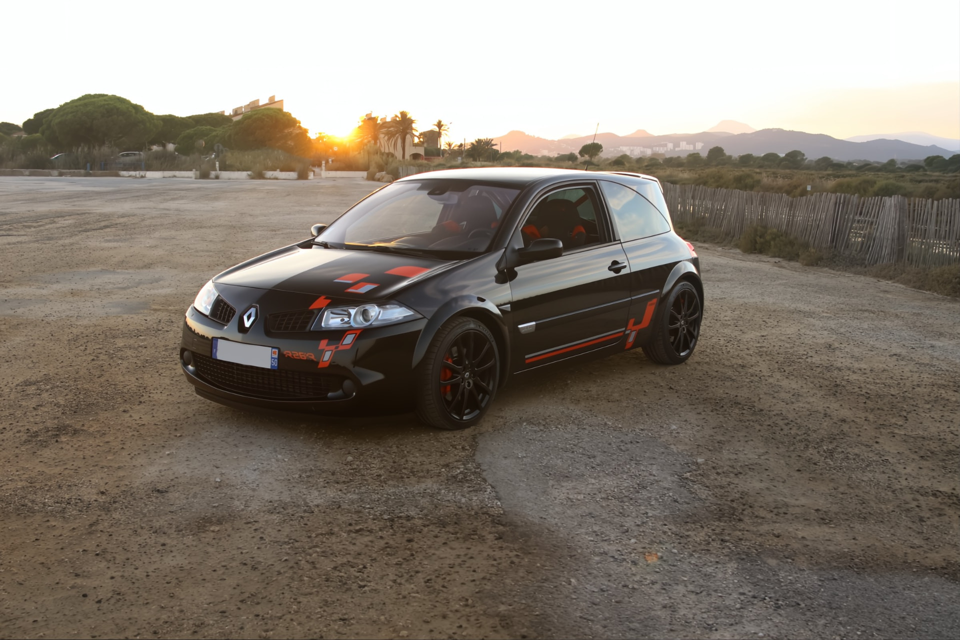 Mégane R26.R noire de trois quarts avant au soleil couchant