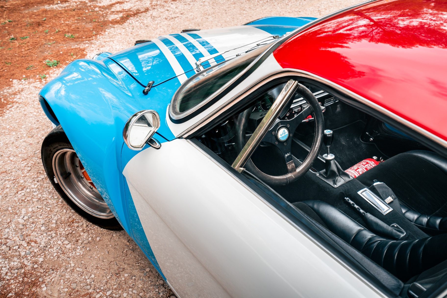 Détail de l'Alpine A110 1800 VB Bis : livrée bleu-blanc-rouge, rétroviseur obus et arceau