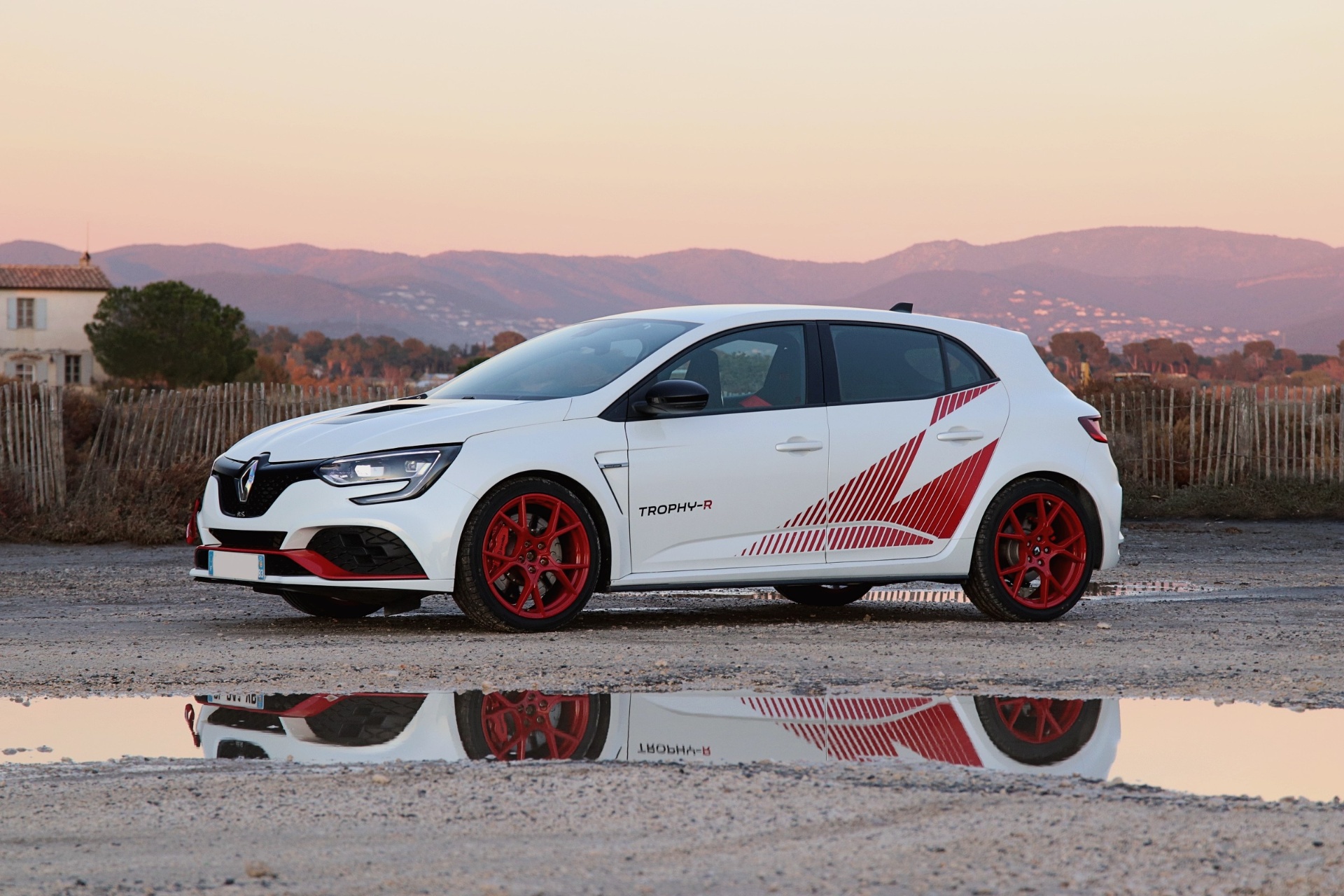 Mégane 4 R.S. Trophy-R blanche de profil au coucher du soleil avec reflet dans une flaque d'eau