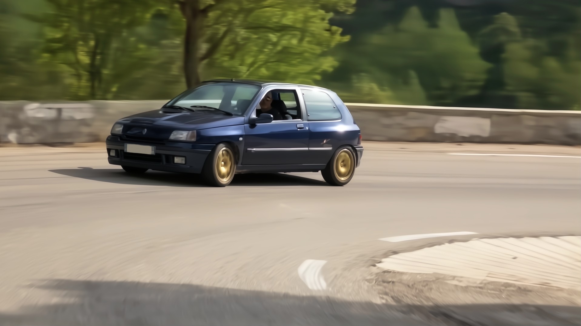 Renault Clio Williams bleue en virage sur route de montagne