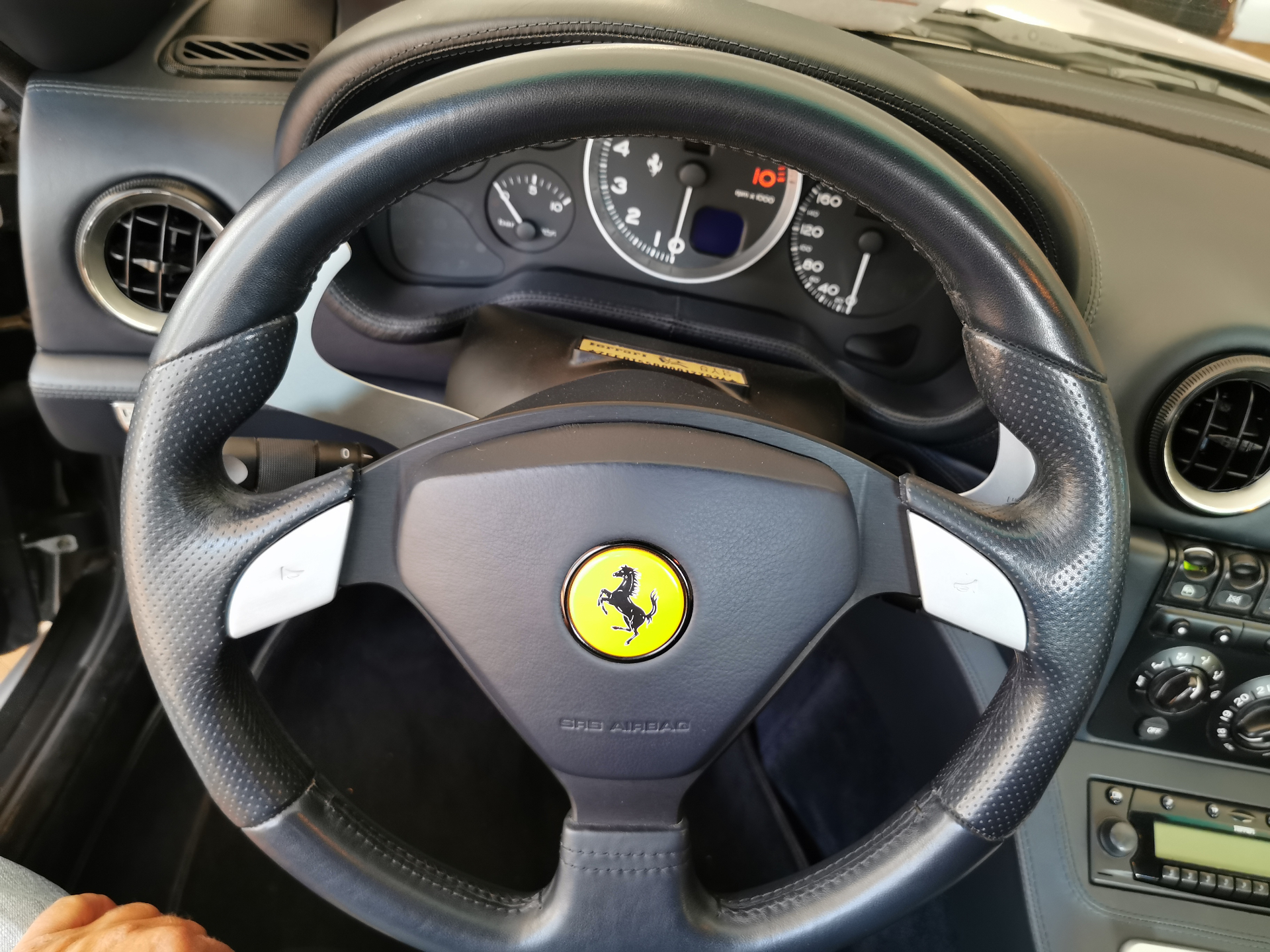 Volant Ferrari 575 et instrumentation évoquant le rapport charnel à la conduite manuelle.