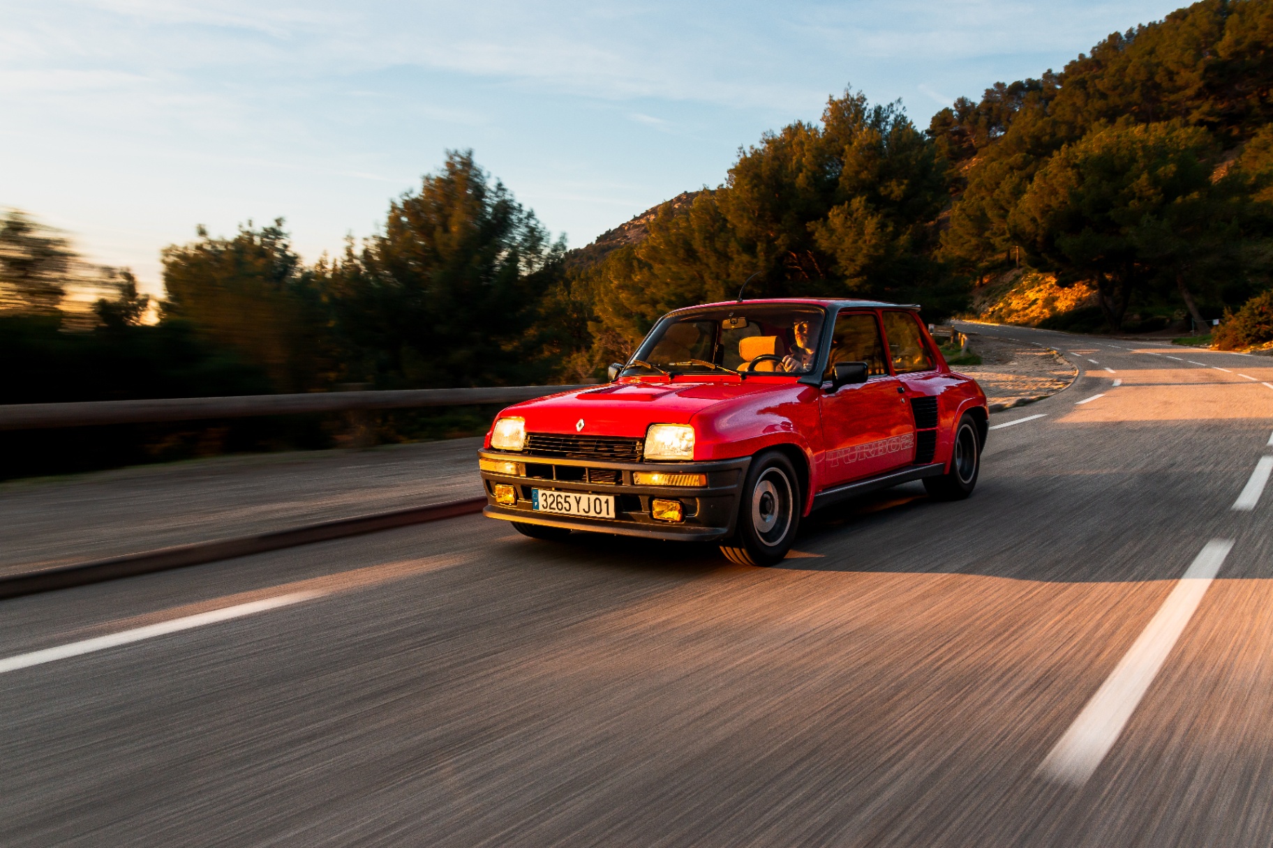 Renault R5 Turbo 2 rouge en mouvement sur route de montagne, trois-quarts avant