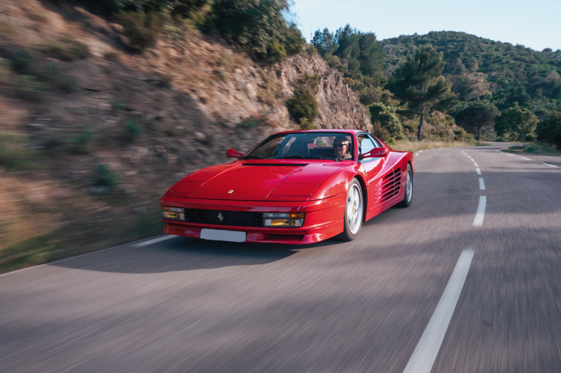 Ferrari Testarossa rouge en action sur une route de montagne