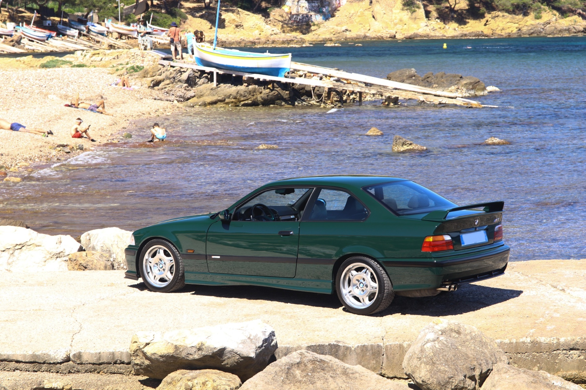 BMW M3 GT E36 de profil sur une jetée face à une calanque
