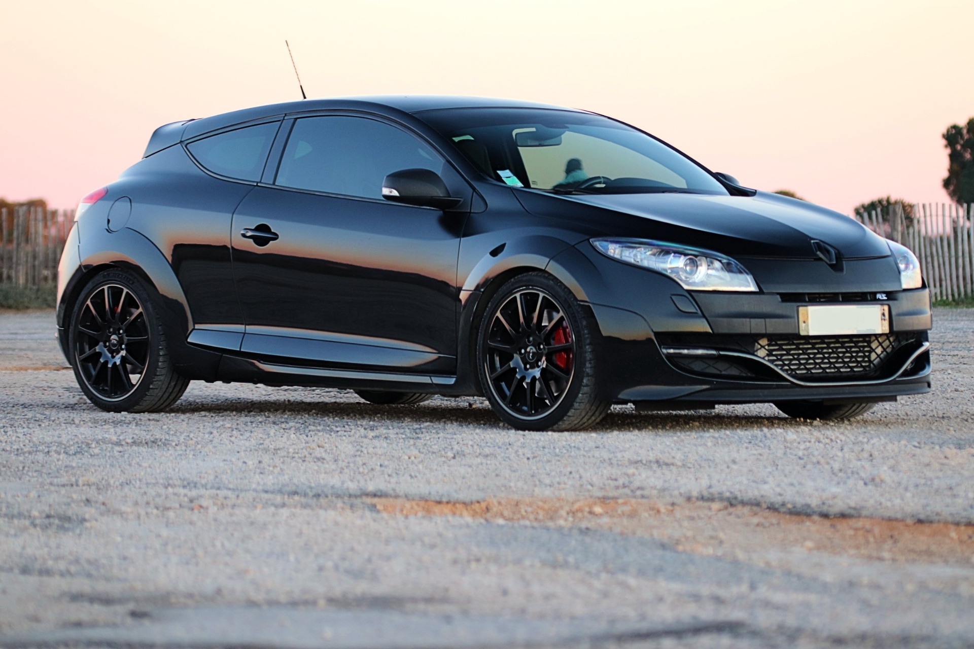 Renault Mégane 3 RS noire de trois quarts avant au coucher du soleil