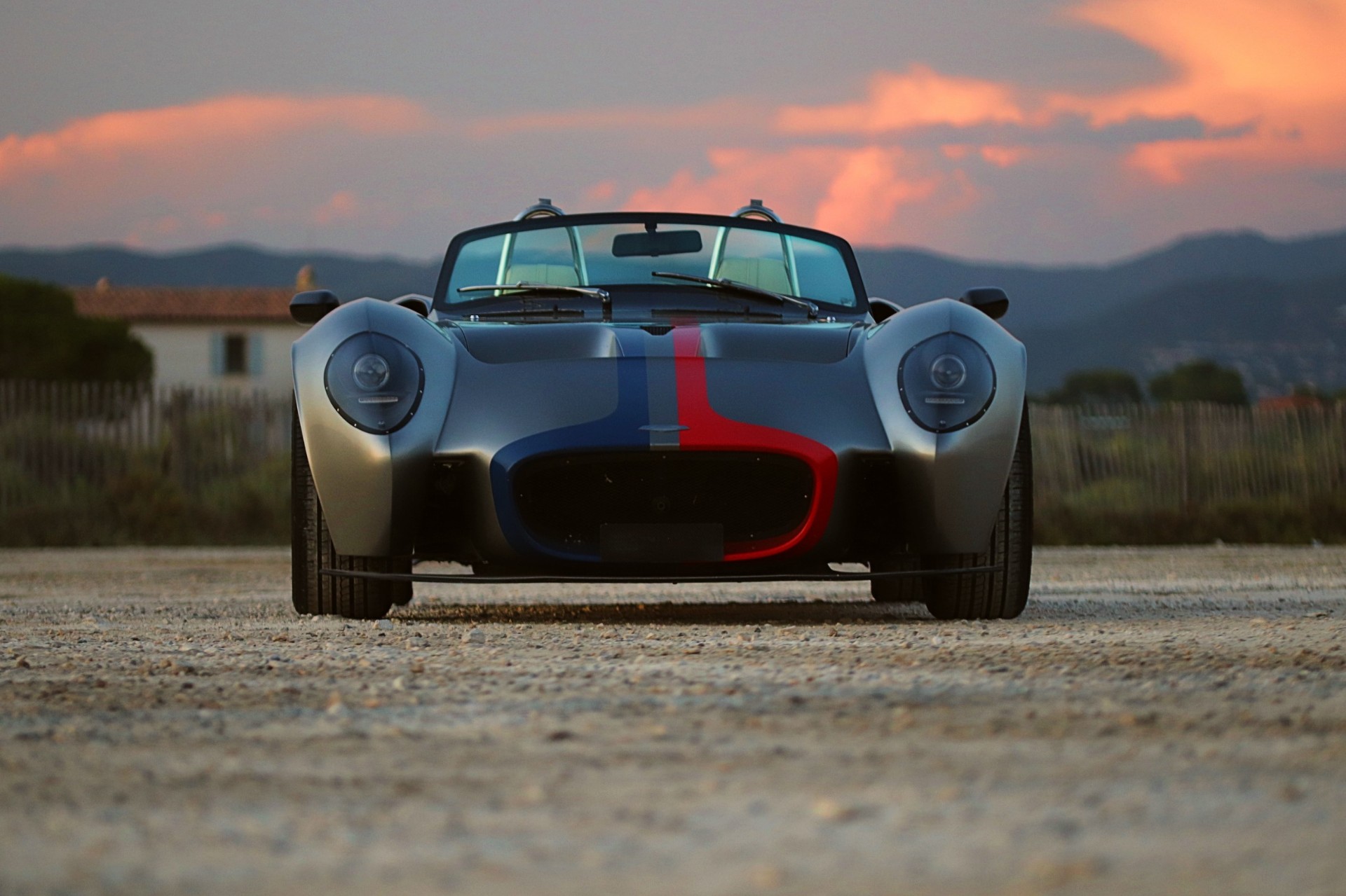 Jannarelly Design-1 grise à bandes bleu et rouge, vue de face au crépuscule.