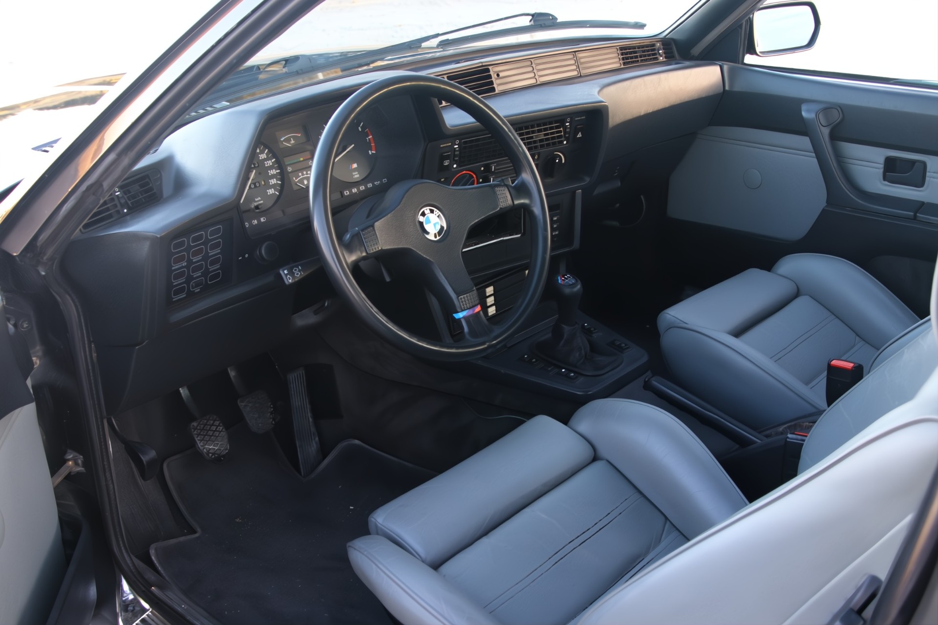 Intérieur BMW M635 CSi avec volant M-Tech, cuir gris clair et tableau de bord d'époque
