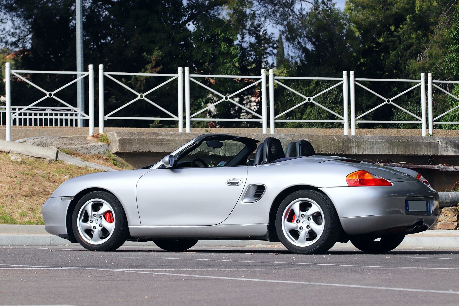 Porsche Boxster 986 S argent de profil, capote ouverte, photographié sur un parking en extérieur