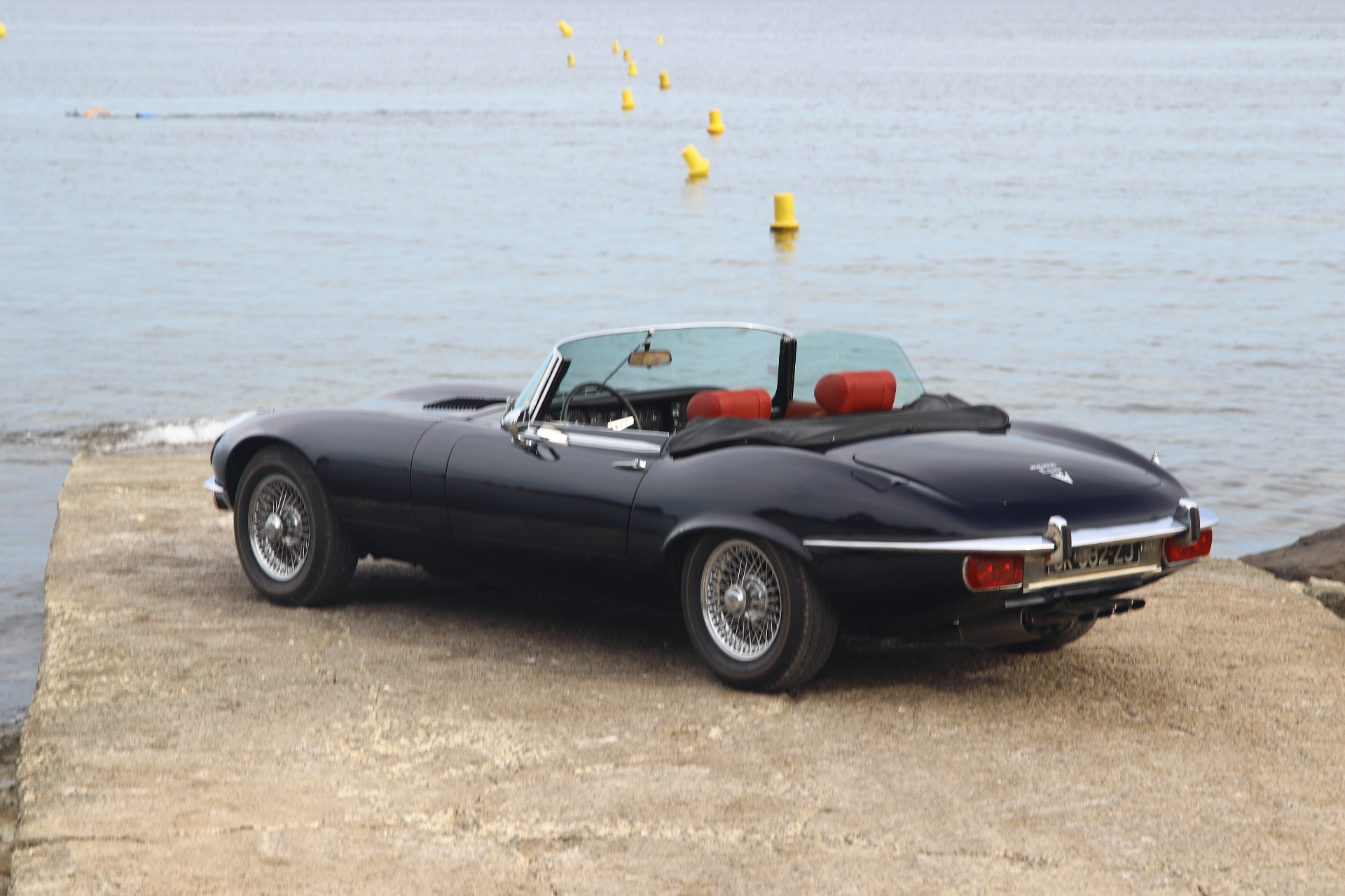 Jaguar Type E cabriolet bleu nuit au bord de l'eau