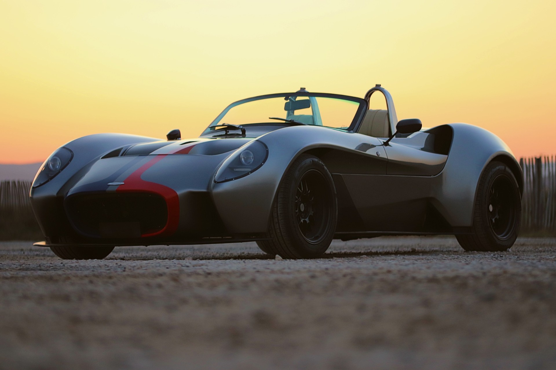 Jannarelly Design-1 grise à bande rouge, vue de trois quarts avant au coucher de soleil.