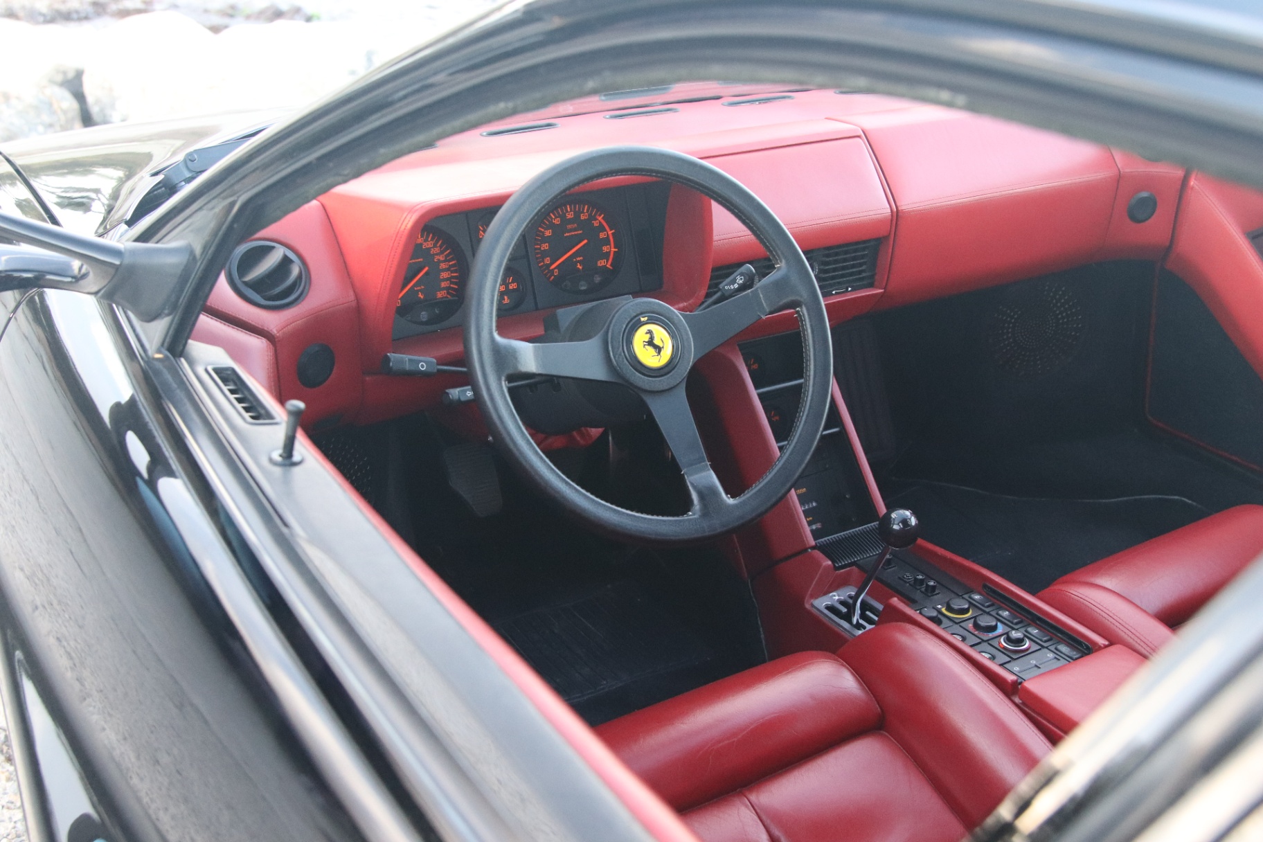 Intérieur de Ferrari Testarossa avec levier manuel et habitacle rouge.