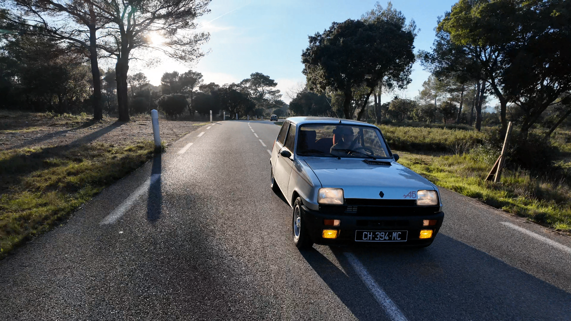 Renault 5 Alpine roulant sur une route de campagne ensoleillée