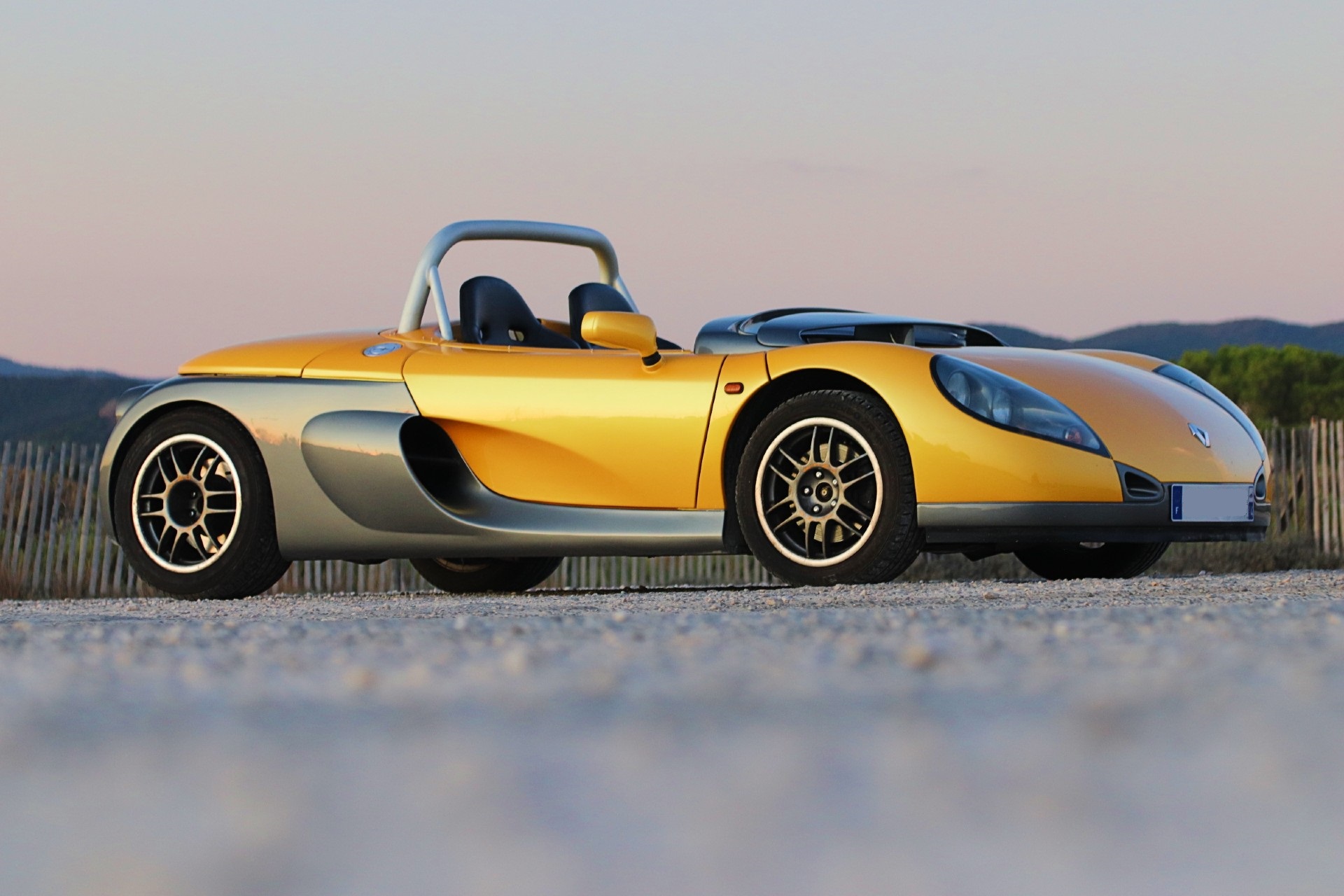 Renault Spider Sport jaune et gris de trois-quarts avant au coucher du soleil