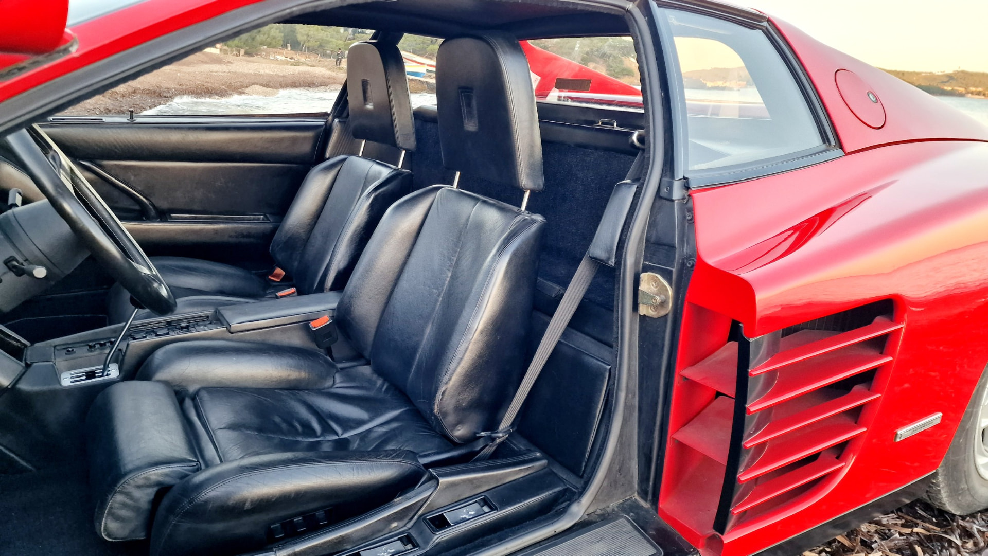 Sièges cuir noir d’une Ferrari Testarossa vus par la portière ouverte