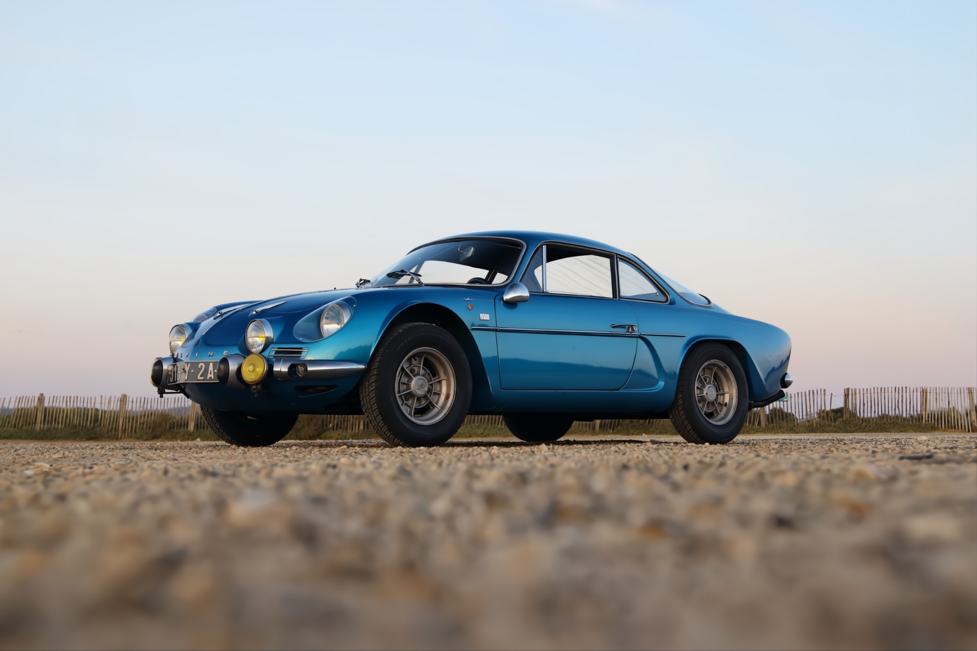Alpine A110 bleue de profil dans un parc