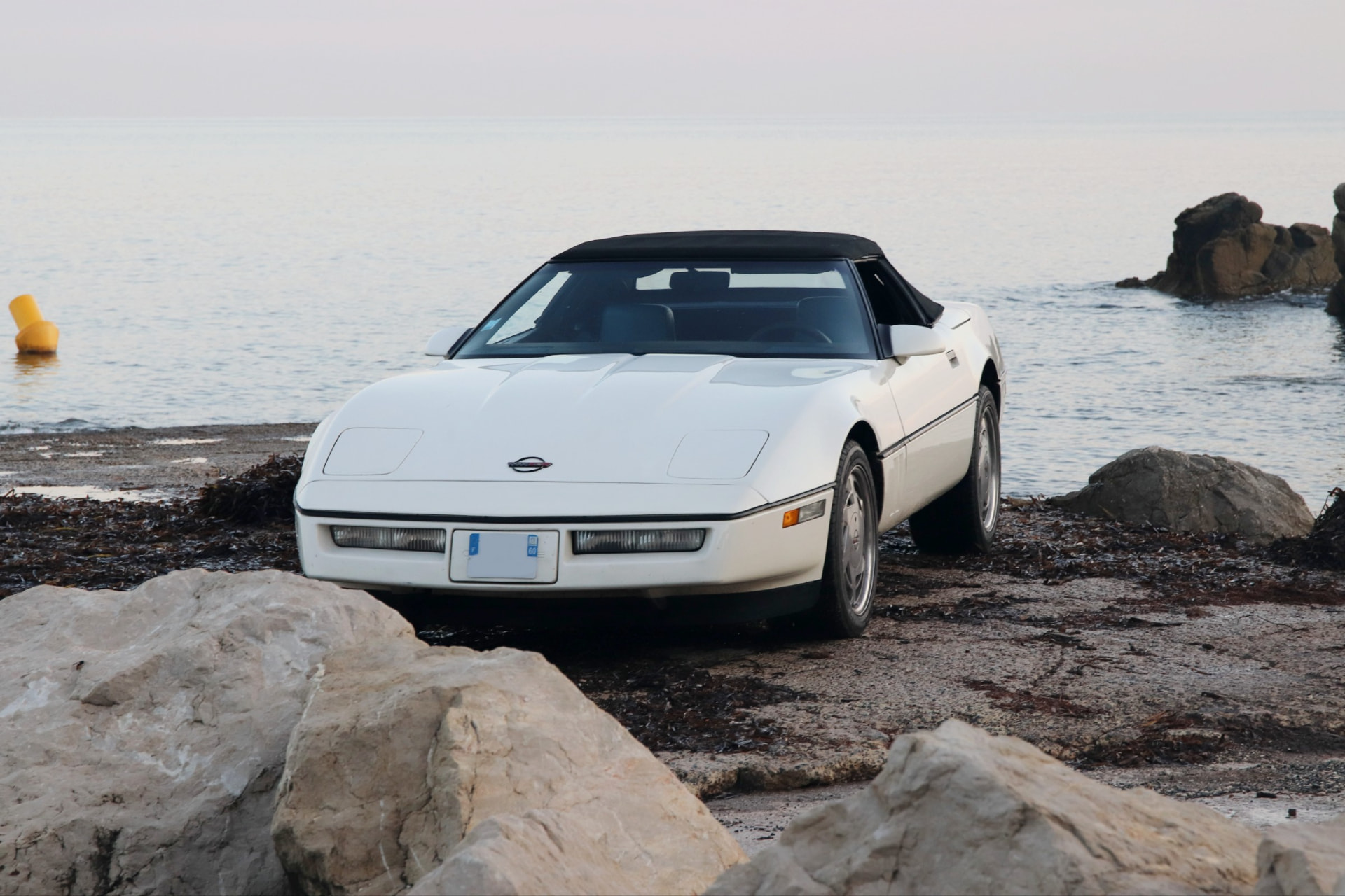Corvette C4 cabriolet blanc de face au bord de l'eau