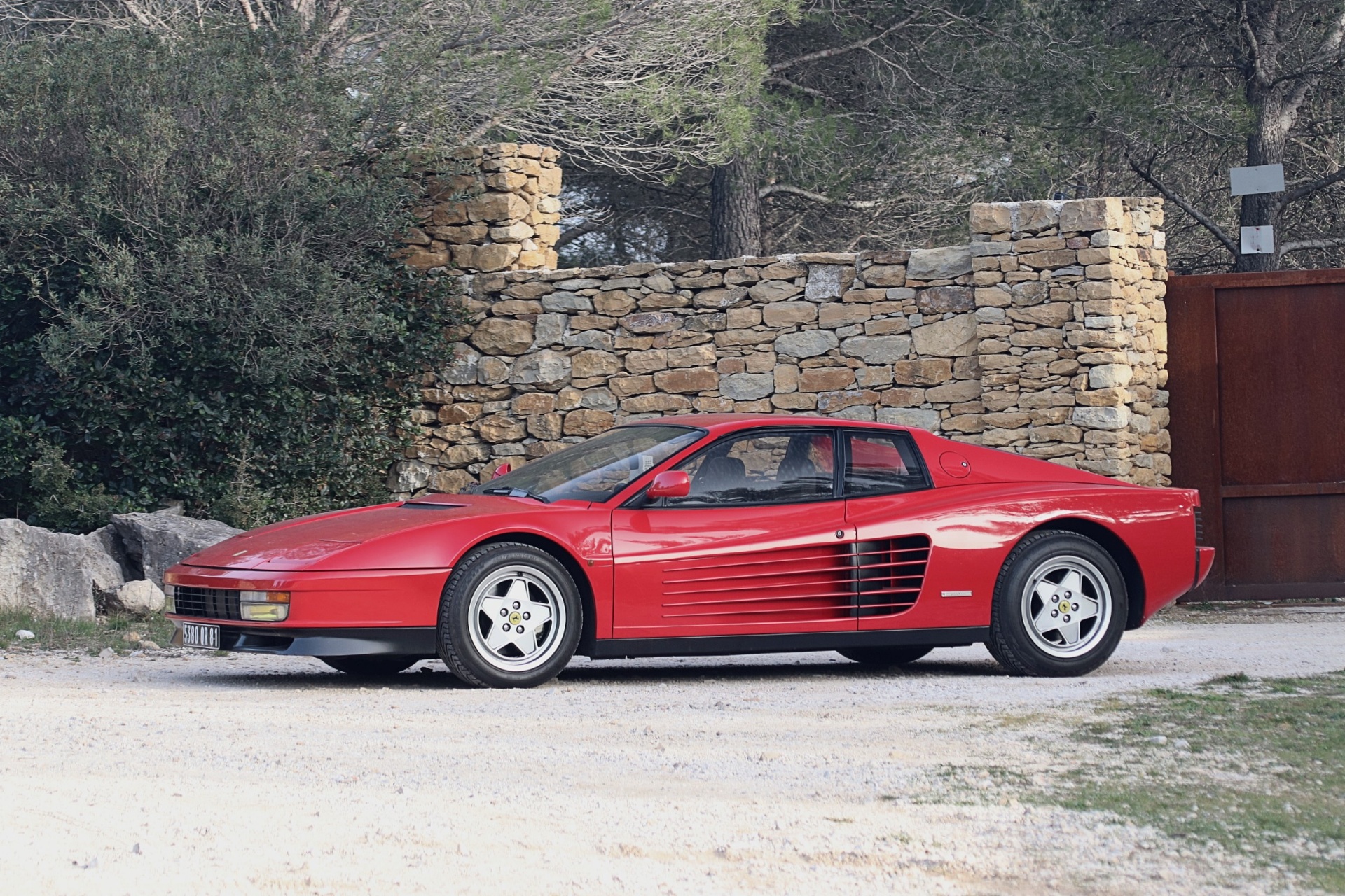 Coupé youngtimer rouge des années 90 dans un décor urbain au coucher du soleil