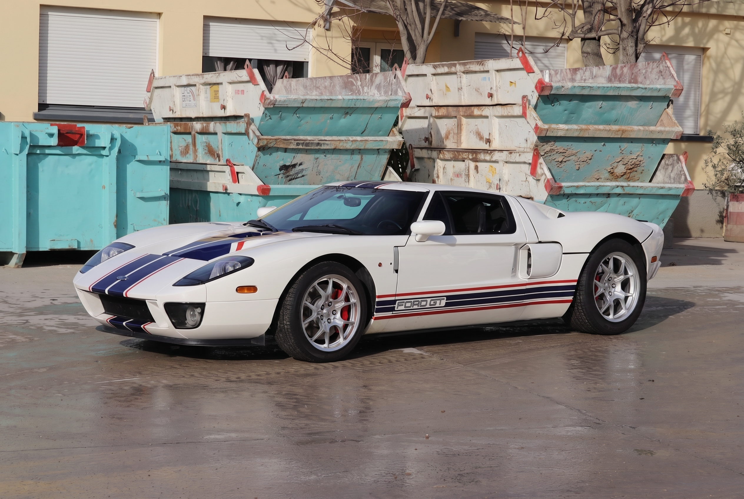 Ford GT blanche à bandes bleues garée devant des bennes